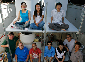 The Caltech team (top left to right - Hao Zhang, Yan Qu, Daejung Kwon - bottom middle from left to right - Clement Cid, Asghar Aryanfar, and Kangwoo Cho, along with members of the Caltech facilities team) in front of the toilet system, which includes a Western-style toilet, a urinal, and a squat toilet.