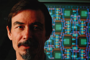 Mead in front of computer chip from the 80s Dr. Mead